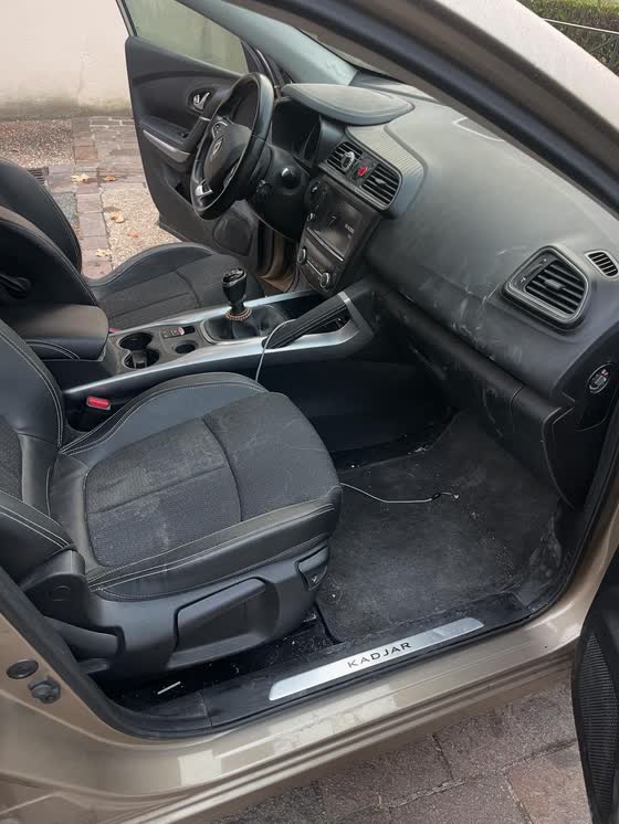 Intérieur avant d'un Renault Kadjar avant nettoyage : tableau de bord poussiéreux et tapis encrassé